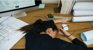 Women resting head on desk, stressed out.